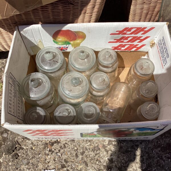 Vintage glass storage jars in a cardboard box, ideal for kitchen storage.