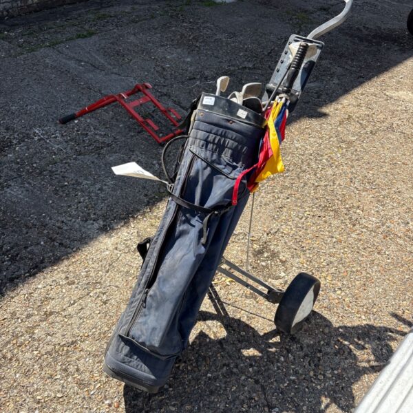 Vintage golf kart with clubs and bag on a paved surface.