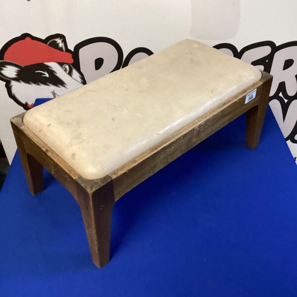 Vintage leather footstool with wooden frame, classic retro style.