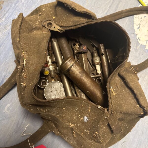 Vintage leather tool bag filled with antique tools and workshop implements.