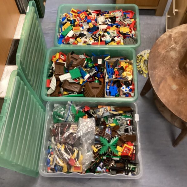 Three green boxes filled with a large collection of vintage Lego building blocks.