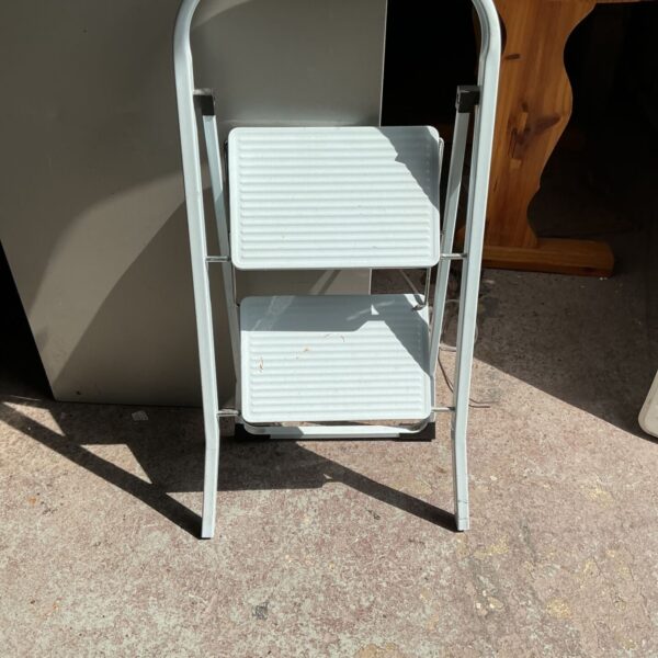Vintage metal two-step ladder, folded for storage.