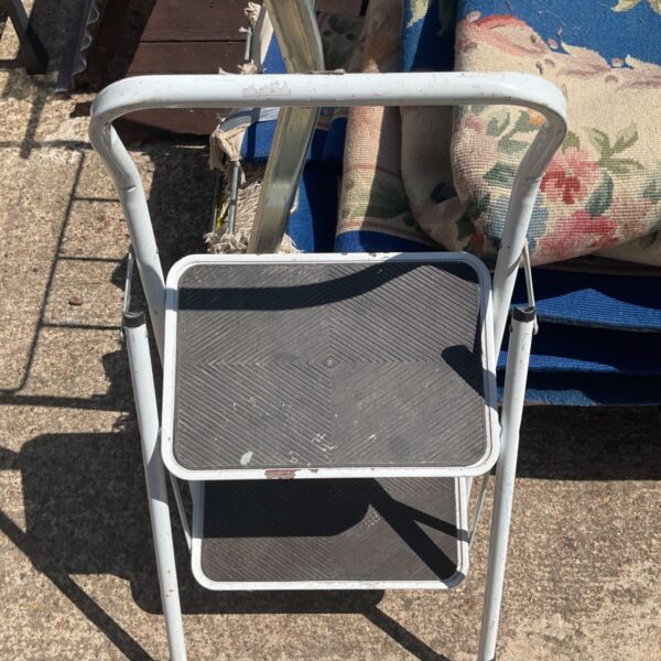 Vintage metal step ladder with plastic treads, folded for storage.
