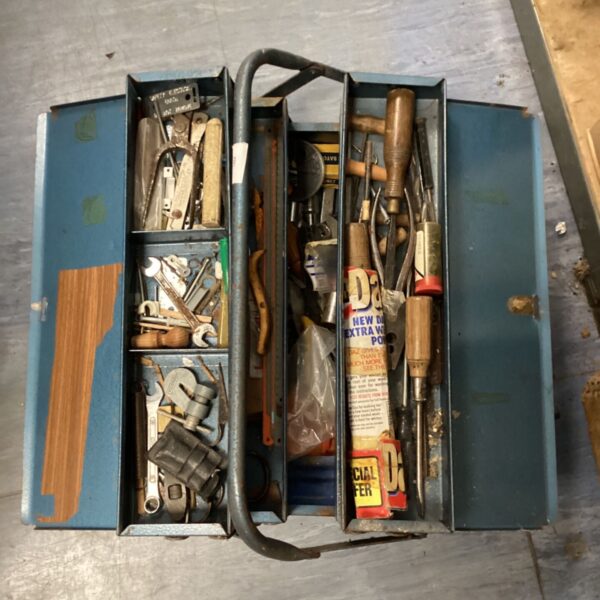 Open vintage metal tool box filled with various tools.