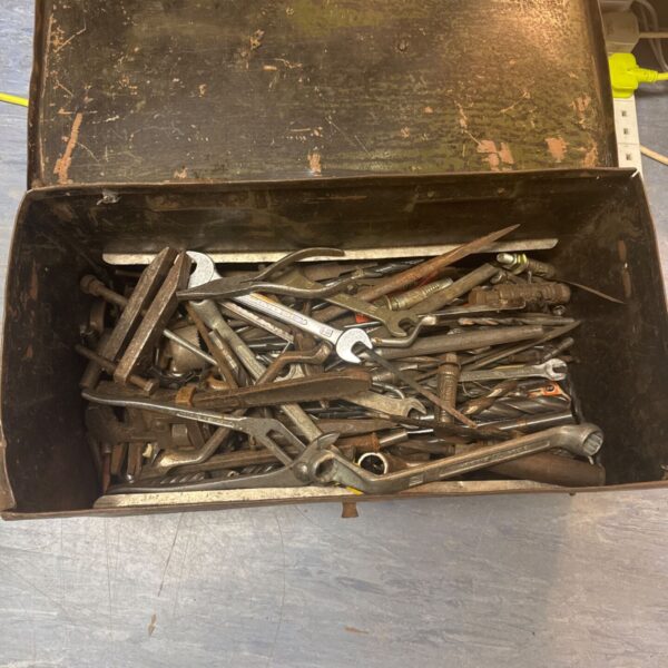 Vintage metal toolbox filled with a variety of old tools.
