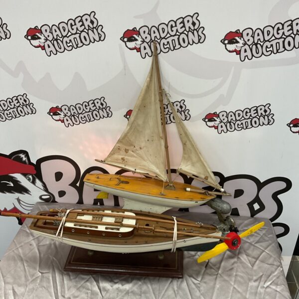 Vintage model pond yacht with fabric sail and wooden hull.
