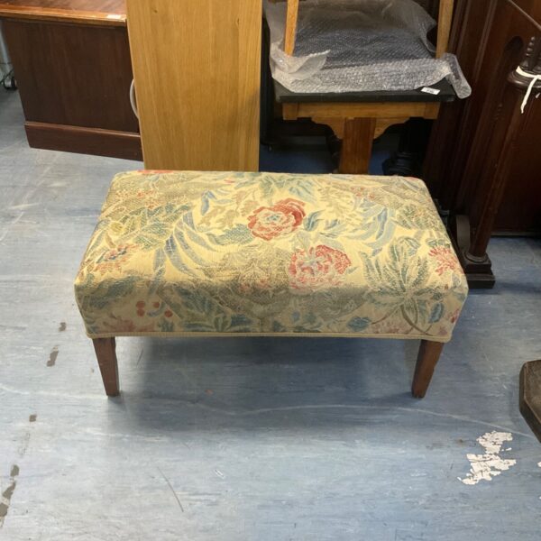 Vintage needlepoint footstool with floral design and wooden legs.