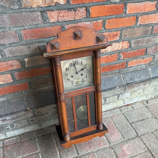 Vintage oak wall clock with Roman numerals and pendulum.