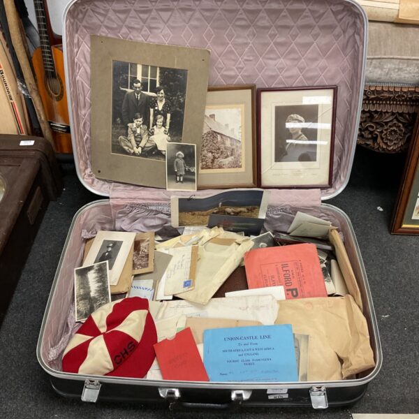 Open suitcase filled with vintage photos and ephemera.