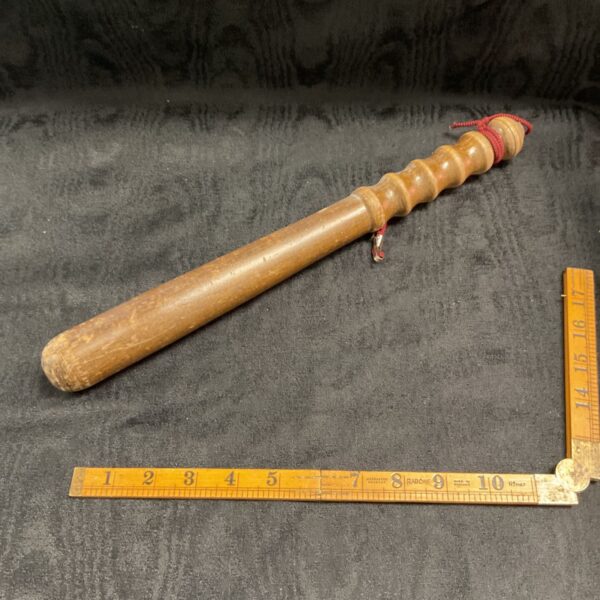Vintage wooden police truncheon with leather strap, collectible item.