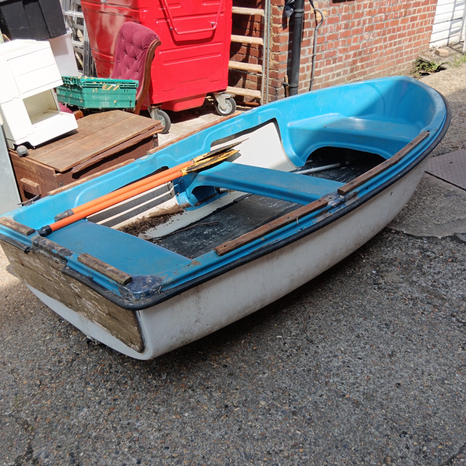 Blue and white vintage row boat with oars in a garden setting.