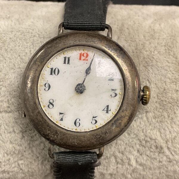 Close-up of vintage silver wristwatch with fabric strap.