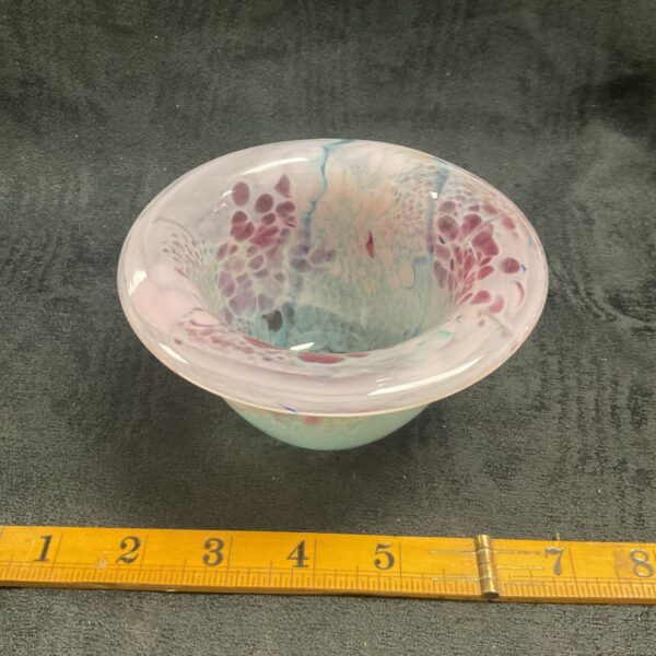 Close-up of vintage studio glass bowl with pink and teal swirls.