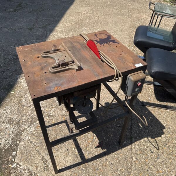 Vintage metal table saw with Crompton Parkinson motor in a workshop setting.