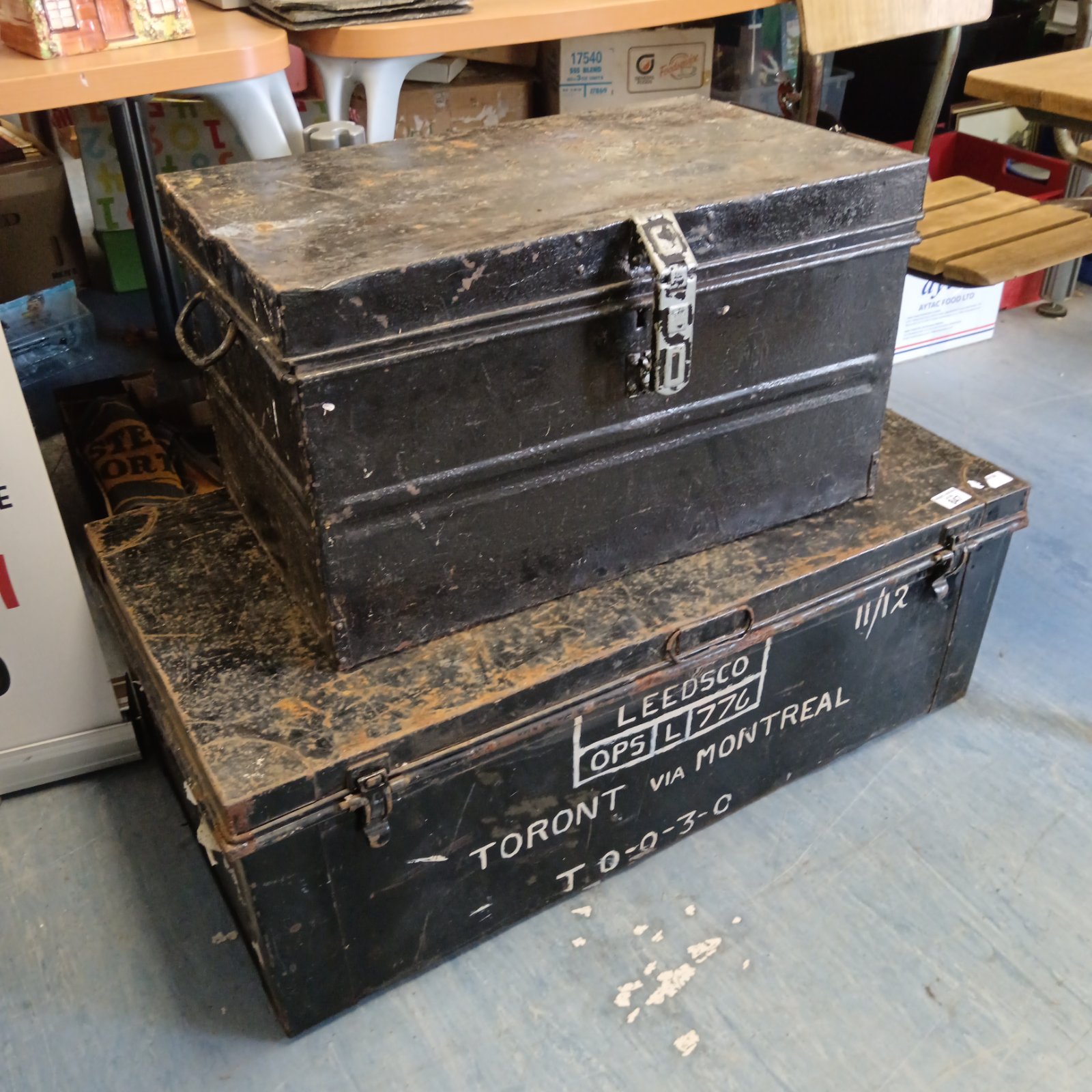 Stacked vintage tin trunks with antique tools, showing wear and patina.