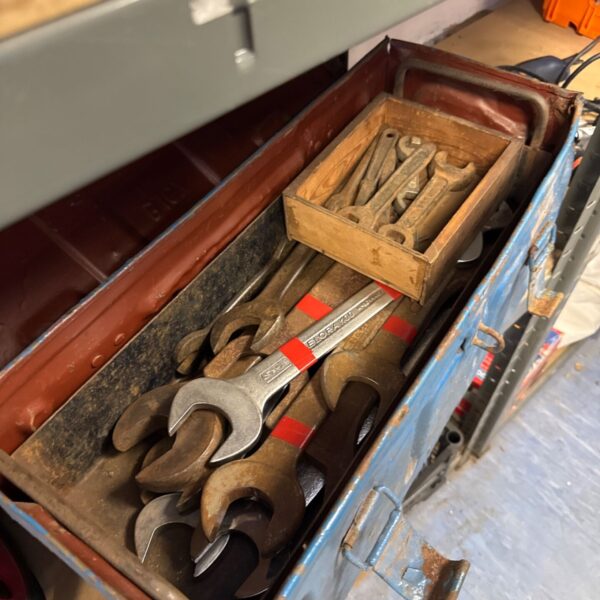 Vintage metal toolbox filled with various spanners and wrenches.