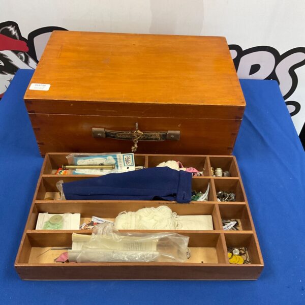 Open vintage wooden sewing box filled with colourful sewing supplies.