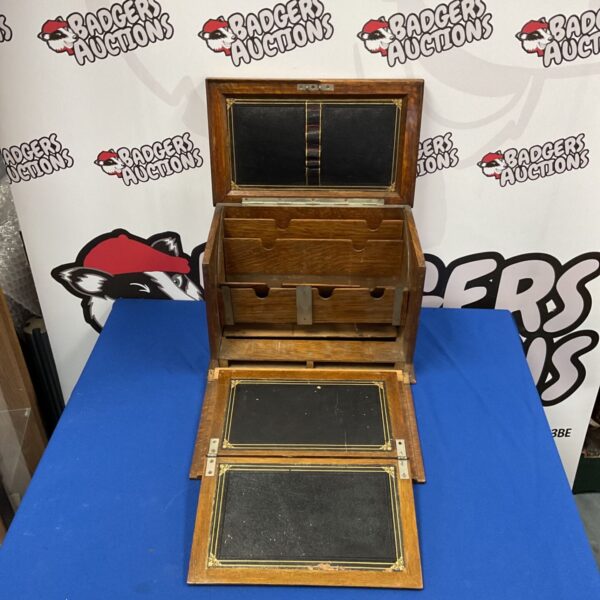 Vintage wooden writing slope with open compartments and a damaged writing surface.