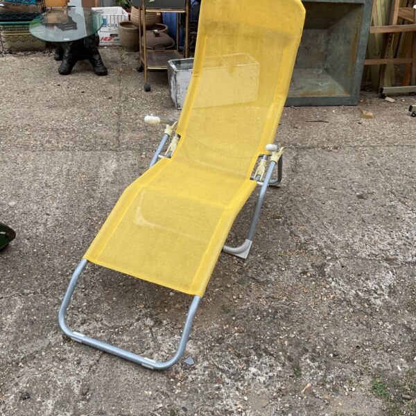 Vintage yellow sun lounger in a garden setting.