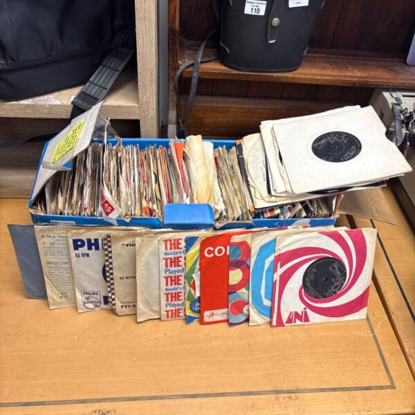 Vintage vinyl singles collection in a cardboard box.