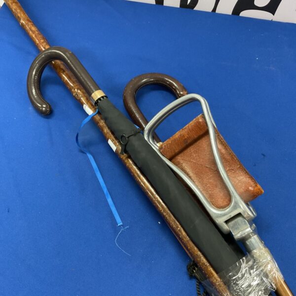 Bundle of vintage walking sticks and umbrellas on a blue background.