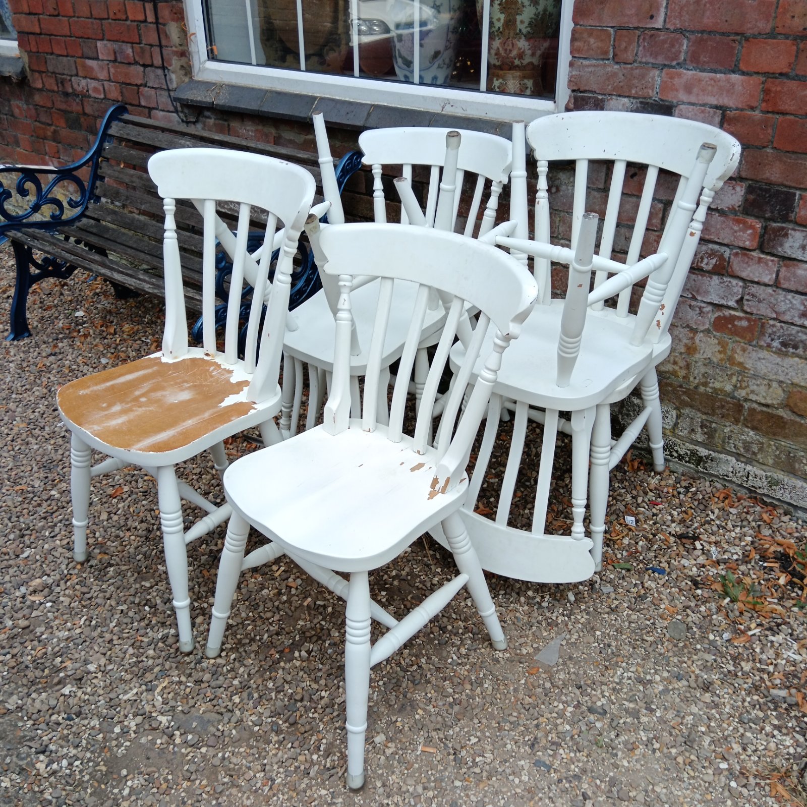 Set of six white painted oak dining chairs in a garden setting.