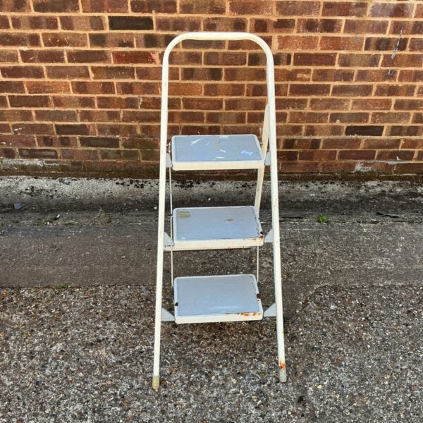 Vintage white metal step ladder for household use.