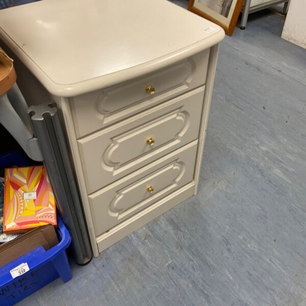 White three-drawer bedside unit for bedroom storage.