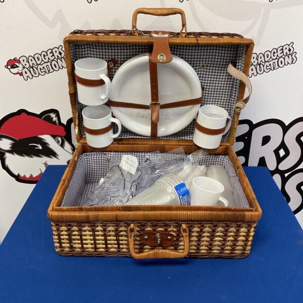Vintage wicker picnic basket with ceramic dining set inside.
