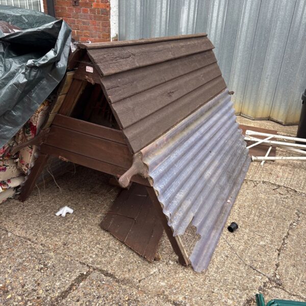 Rustic wooden chicken coop in a garden setting.
