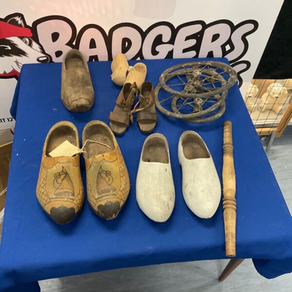 Antique wooden clogs displayed with vintage pram wheels, a collectible lot.