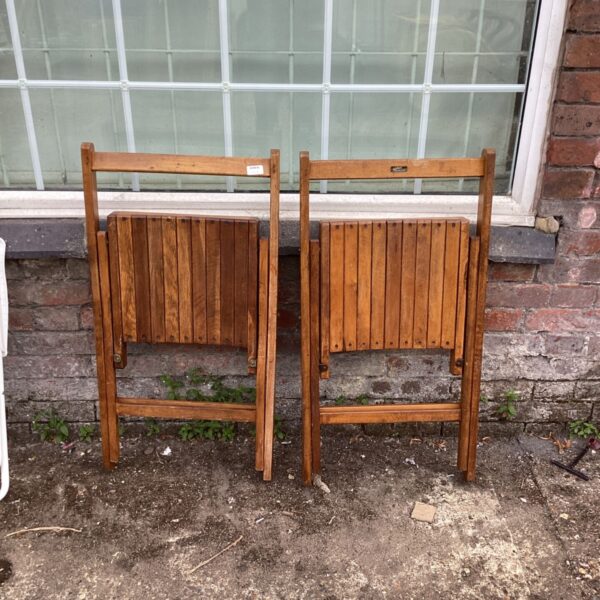 Pair of vintage wooden folding garden chairs in a garden setting.