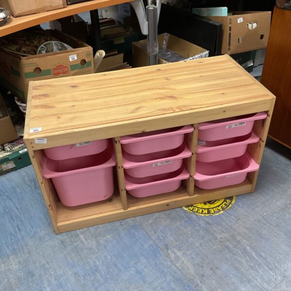 Wooden storage unit with nine pink trays for home organization.