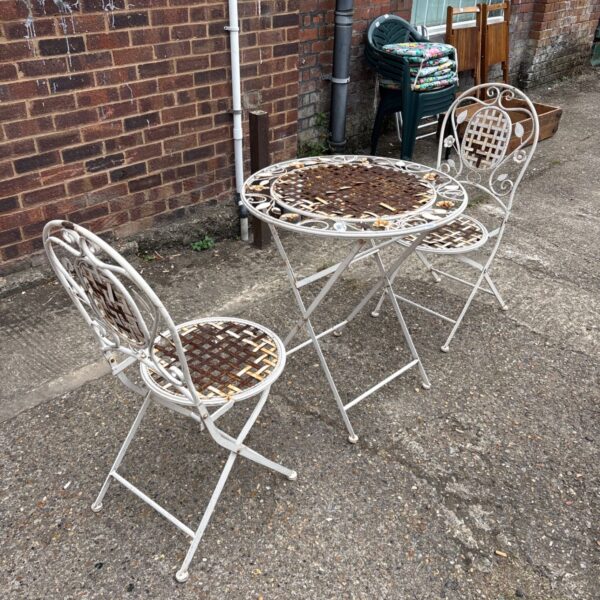 Vintage wrought iron garden table and chairs set in a garden.