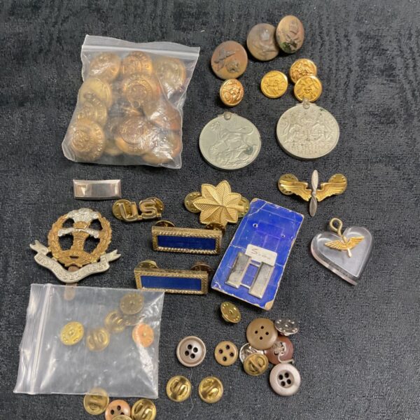 Mixed lot of WWII military badges, medals, and buttons for collectors.