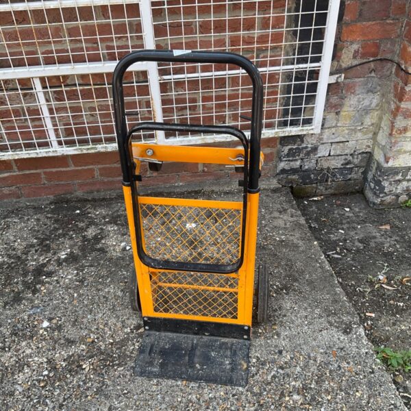 Yellow steel sack truck for moving heavy loads in a workshop.