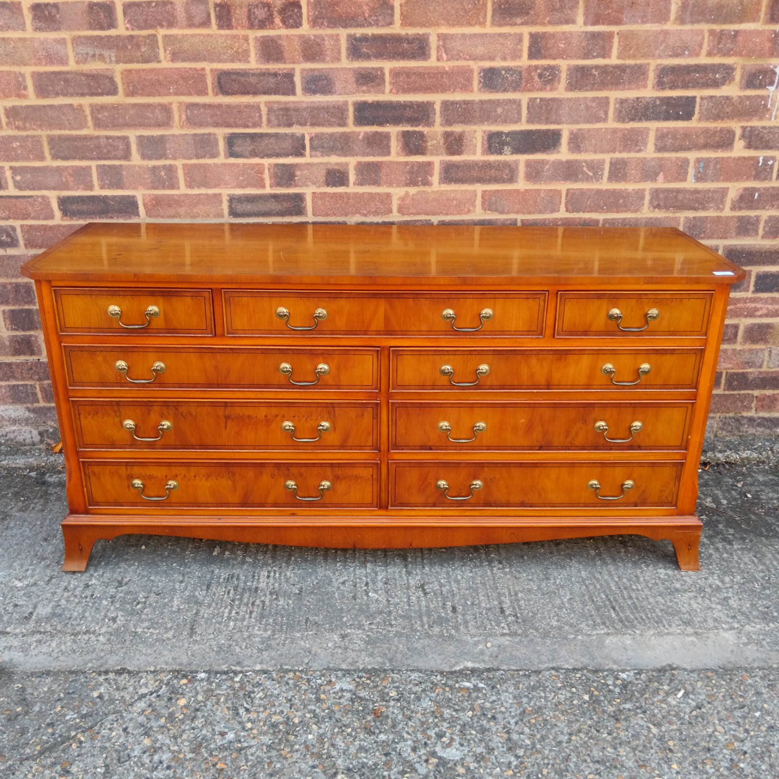 Antique yew wood chest of drawers with brass handles.