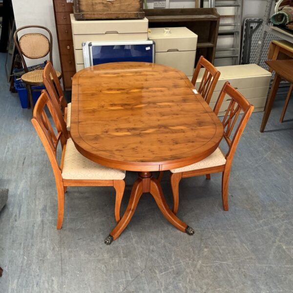 Antique yew wood dining set with extending table and four chairs.