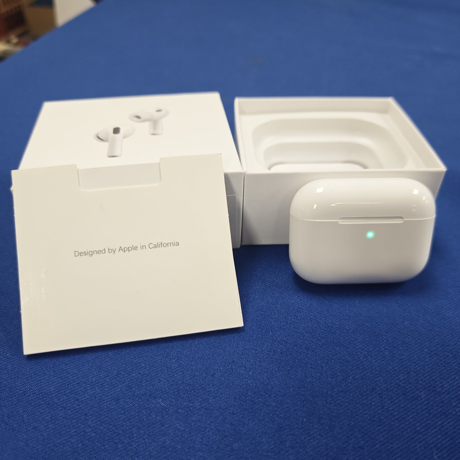 White Air Pod style earbuds and charging case on a white surface.