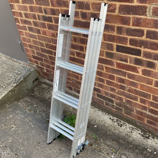 Silver aluminium combination ladder leaning against a wall.
