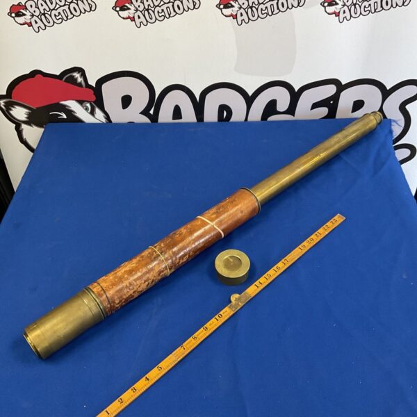 Antique brass telescope with leather binding on a blue background.
