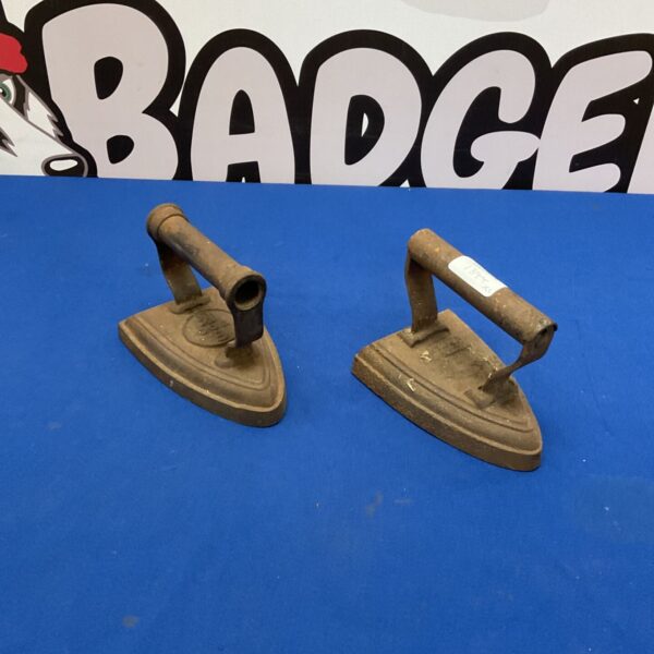 Antique cast iron flat irons with wooden handles, vintage laundry tools.