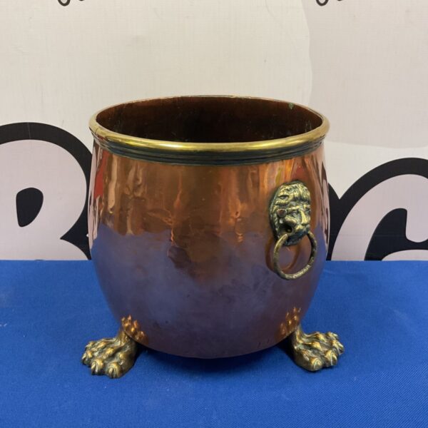 Antique copper planter with lion head handles and claw feet.