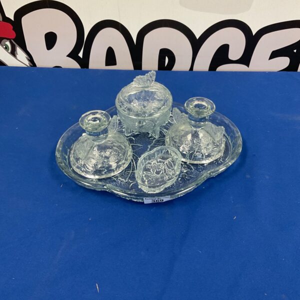 Antique cut glass dresser set with silver tops on a patterned surface.