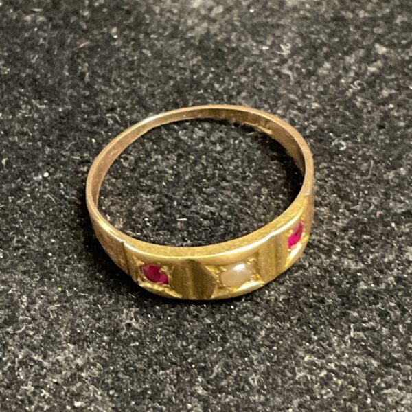 Antique gold ring with red stones and pearl detail.