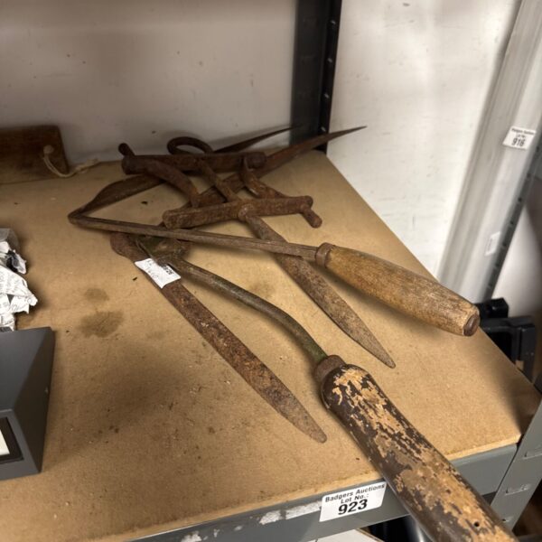 Antique hand scythes with curved blades and wooden handles.
