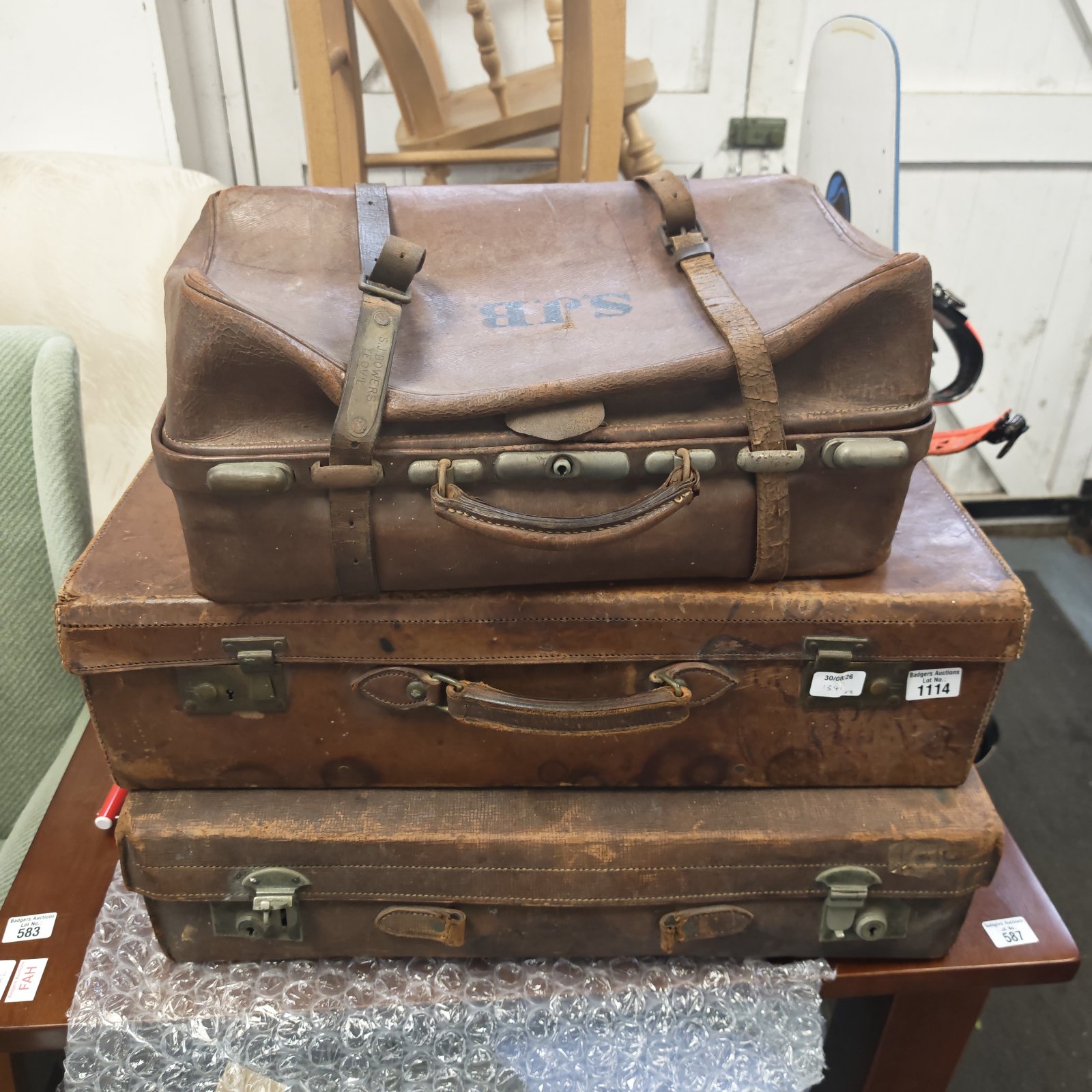 Antique leather suitcases stacked, including one initialed S.J.B.