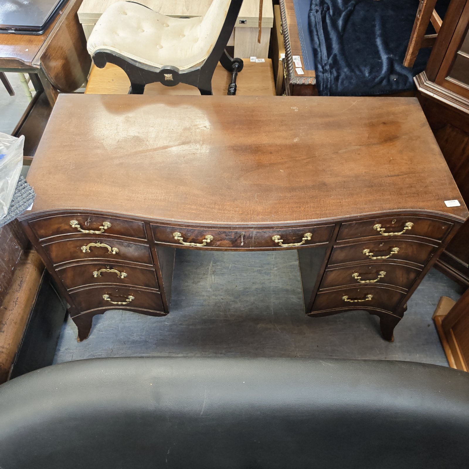 Antique mahogany kneehole desk with brass drawer pulls.