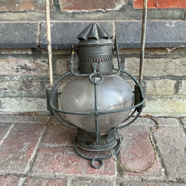 Antique marine lantern against a brick wall.
