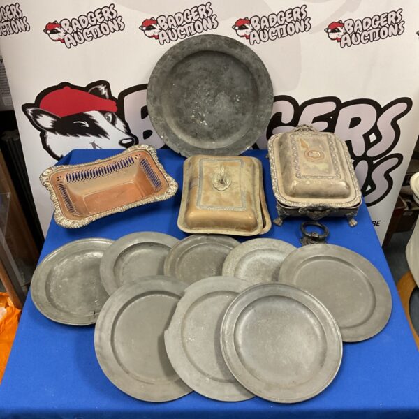Antique pewter plates and copper tureens displayed for auction.